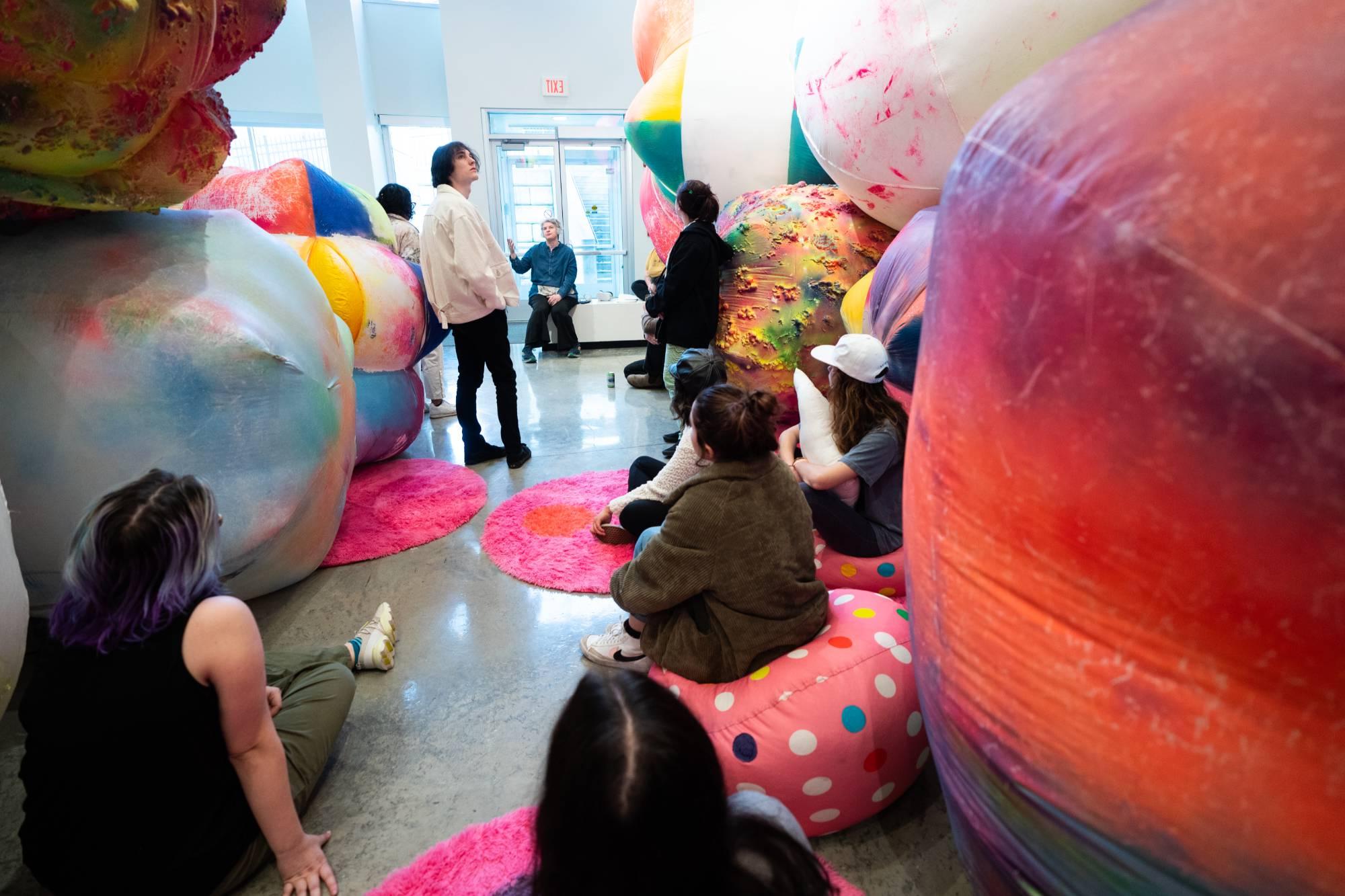 student with brightly colored suitcases of inflatable sculptures